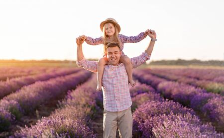 Happy father with daughter in lavender field at sunset.の写真素材
