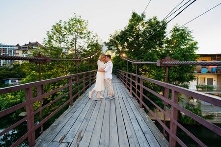 a couple a man and a woman in white on a wooden bridge over the Dagomys river in the summer in Sochiの写真素材