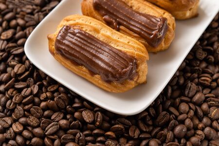 custard cakes with chocolate icing on coffee beans. Close-up.