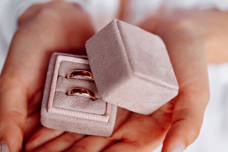 wedding rings in a pink box in the hands of the bride.