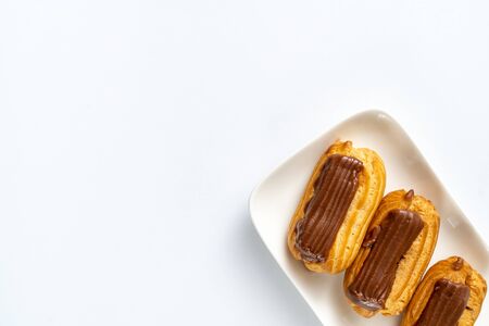 copy space. fragment plate custard cakes with chocolate icing and coffee on a white background.の写真素材