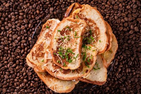 croutons sprinkled with grated cheese and green, background coffee beans. close-up.