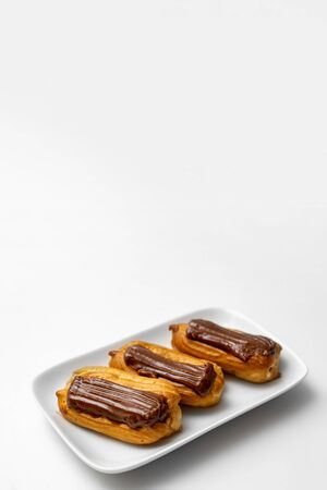copy space. fragment plate custard cakes with chocolate icing and coffee on a white background.