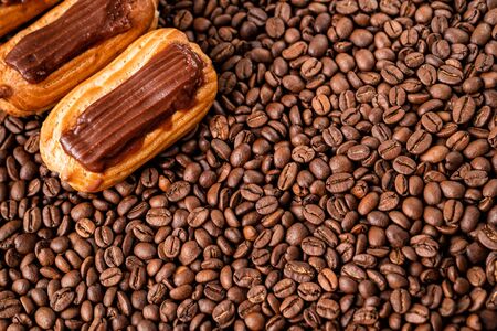 cakes with chocolate icing on coffee beans. copy space.