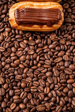 one custard cake with chocolate icing on coffee beans. Close-up. copy space.