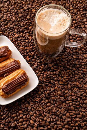 big white Cup of coffee next to custard cake, on the background of coffee beans.の写真素材
