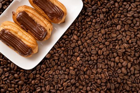 copy space. custard cakes with chocolate icing on coffee beans. Close-up.