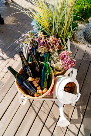 white watering can, empty green bottles, corks and flowers decor in the open air top viewの写真素材