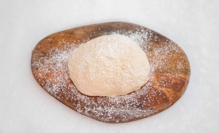 yeast dough for pizza on a white table on a wooden Board. copy space.の写真素材