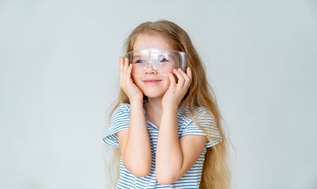 smiling small girl wears safety goggles from dust for experimentsの写真素材