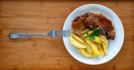 meat and potatoes on a white plate served with a fork. home cooking. wooden tray. close up. top...