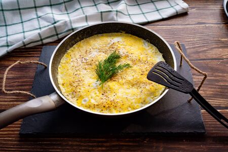 homemade omelet with herbs in a frying pan on a wooden table. home cooking.の写真素材
