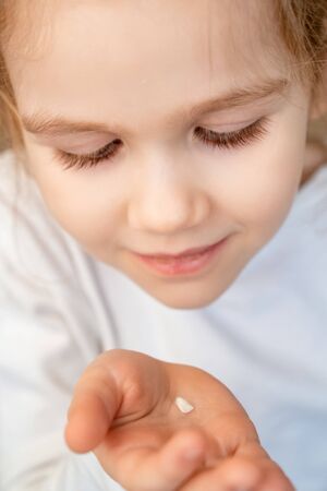 little blonde girl with the fallen milk tooth in his hand. dental care. tooth fairy. the children...