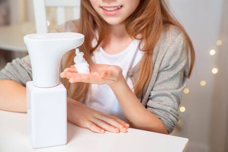 kid hands of disinfect with foam automatic soap dispenser. hygiene and protection against viruses and bacteria.の写真素材