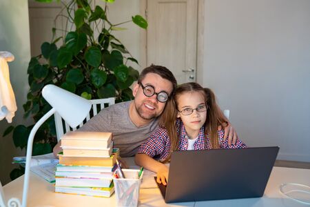 stay home. daddy in glasses helps kid girl  with online lessons on the laptop, distance learning....