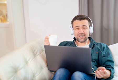 blogger, student or freelancer listens to the audio lesson, book or music with headphones, drinking...