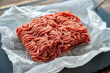 the minced meat on the cooking paper and stone tray. prefabricated patties.
