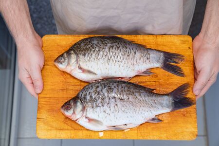 raw whole cleaned from the scales, the fish river carp prepared for baking in the oven in the hands of men.の写真素材