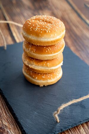 a pyramid of buns with sesame seeds for cooking burgers. on a black stone tray. delicious fast food...