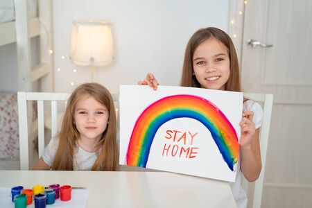 little girls drawing on a white sheet rainbow and write stay home. flashmob chasetherainbow.
