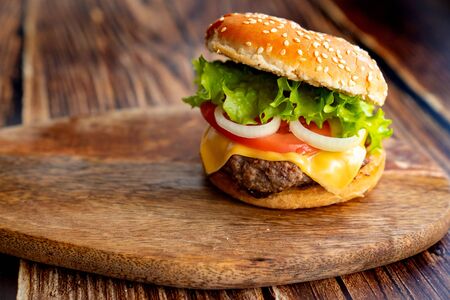 homemade hamburger on a wooden board. bun with sesame, cutlet and vegetables. fast food