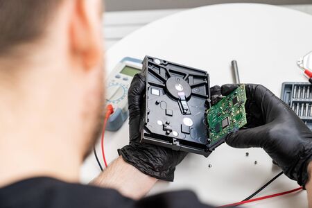 open Computer Hard Drive on white background in Hands in black gloves. master of repair.