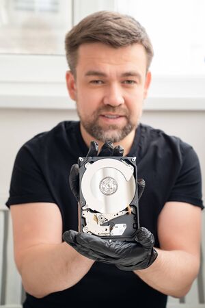 open Computer Hard Drive in Hands in black gloves. master of repair.