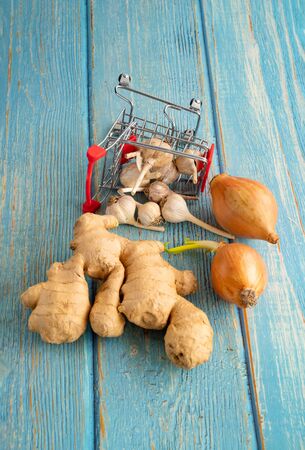 onion, garlic, ginger root in mini shopping cart. increased immunity. on blue wodden background.の写真素材