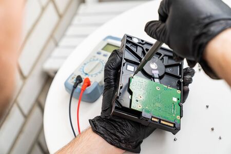 open Computer Hard Drive on white background screwdriver in  Hands in black gloves. master of...