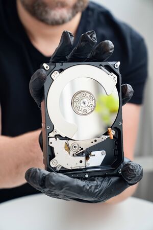 open Computer Hard Drive in Hands in black gloves. master of repair.