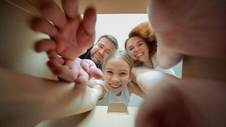 family with daughter looks in the box, is surprised and happy to receive a surprise. family opened a box with a gift.の写真素材