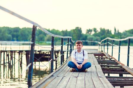 in the summer the man on the old bridge broken bridge on the background river. Pier on the river, naval station.の写真素材