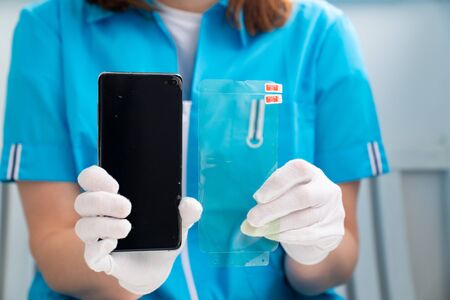 installation of protective cover film on the smartphone. Maintenance support and repairing service...