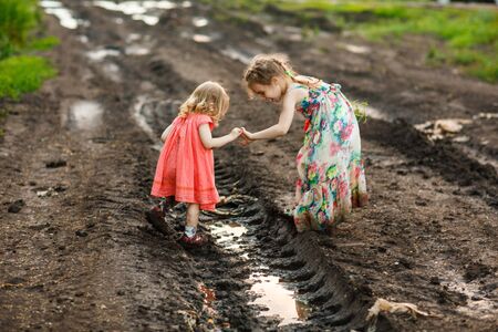 little girls kids in a dress goes in the dirty dirt road. earth after a rain. off-road. near a field...