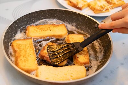 toast with egg in a frying pan fry a little girl. baby hand with a shovel. simple recipes. quick homemade food for Breakfastの写真素材