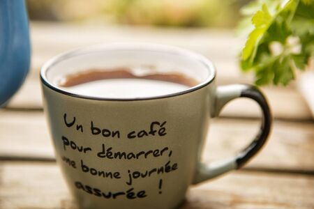 concept of Breakfast and teatime in open air. Tea into mug (inscription on French: good coffee to...