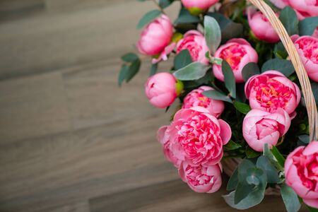 bouquet of pink peonies in a basket on the floor. gift and interior decoration with fresh flowers.の写真素材
