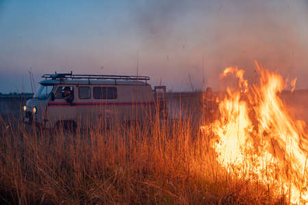 01.05.2020 Russia Rostov-on-don, burns dry grass, in the sky, the smoke and soot. fire extinguish truck emergency rescue, fire. a man in uniform. the environmental problem. firefighters are workingのeditorial素材