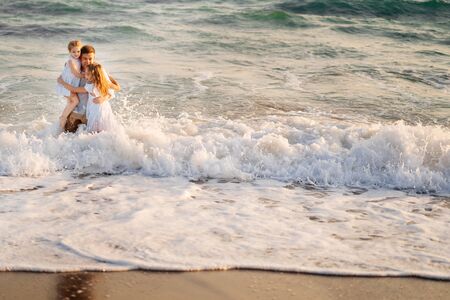 wet dad and daughters swimming in the sea in clothes, playing and having fun together on the beach....