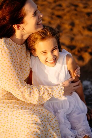 mother with daughter sitting on the sand, on the beach by the sea. the relationship of parents with children. family vacation.の写真素材