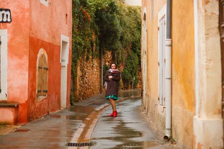the girl walks in the rain on the street of a small town in Provence France. a trip to Europe in the...