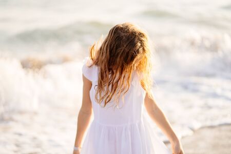 girl walks and fun on the sea shore with big waves and strong winds. a happy childhood and trip.