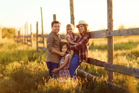 family standing near a fence at sunset in the village.の写真素材