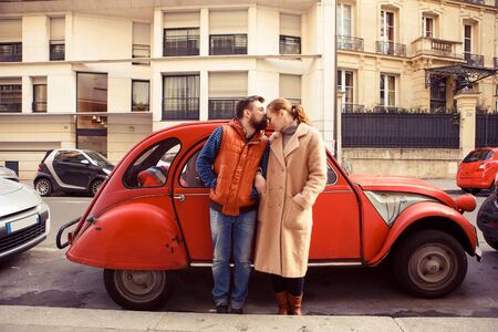 a couple man and woman stand at a red retro car, walking in spring Paris. a romantic trip together. tourism in Europe.の写真素材