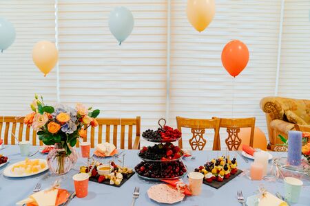 the festive table at a summer children's party in a country house. decoration balloons. catering. a...
