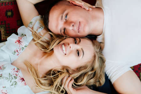 close up. the view from the top. happy couple of young lovers lying on the floor and relax, flirt...