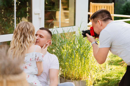 the photographer takes pictures a couple of lovers sitting in the garden in the backyard. the couple...