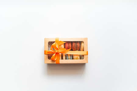 gift box with orange ribbon and colorful macaron inside on a white background.の写真素材