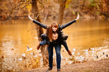 happy couple in love, a man and a woman hug and flirt in an autumn park near the river. romantic...