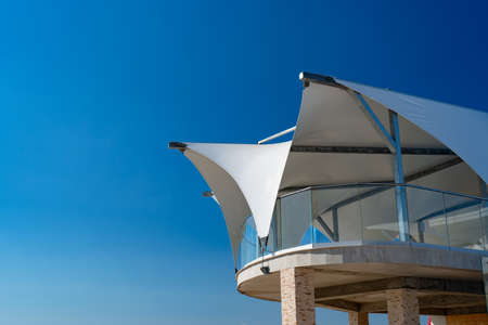 a white veranda, a balcony with a fabric roof against a clear blue summer sky.の写真素材